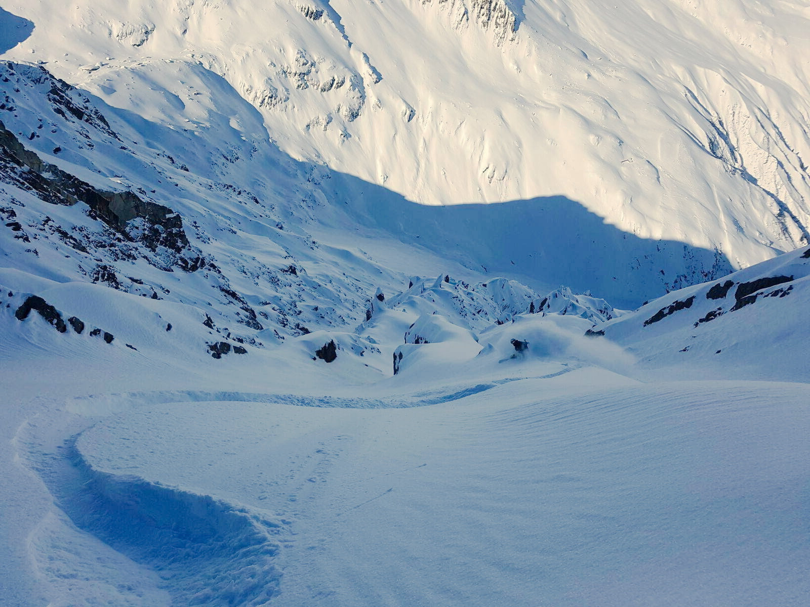 Tiefschneeabfahrt eines Splitboarders im felsdurchsetzten Steilgelände
