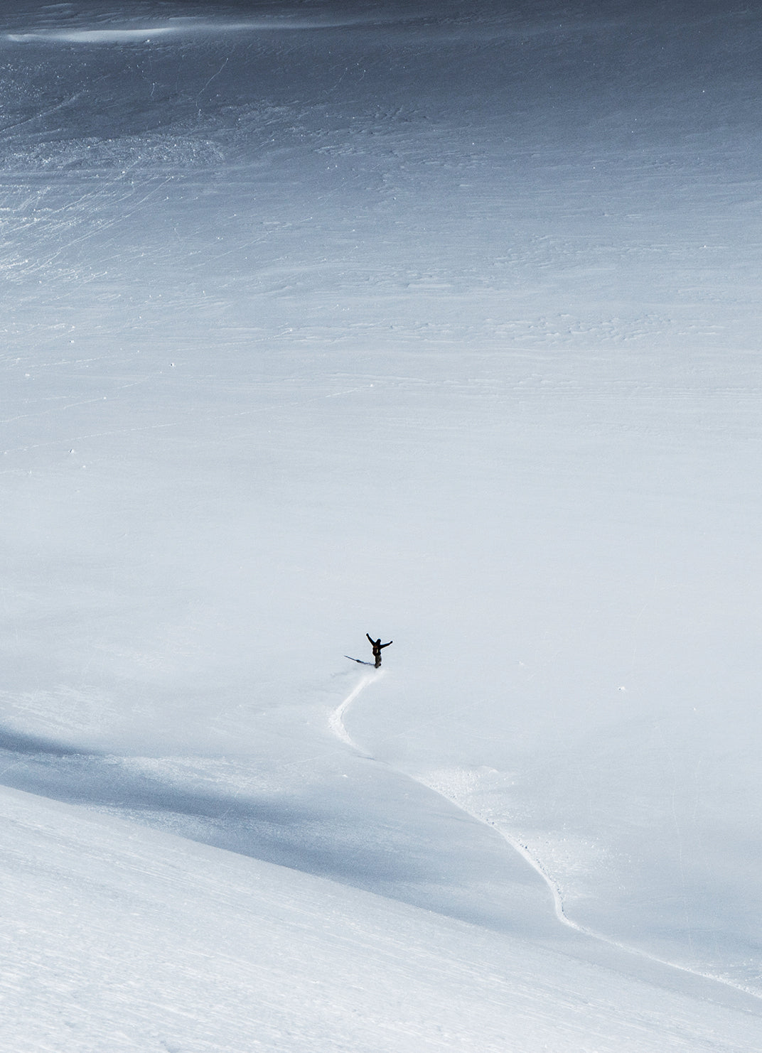 Snowboarder am Ende einer Abfahrt in einem weiten Schneefeld